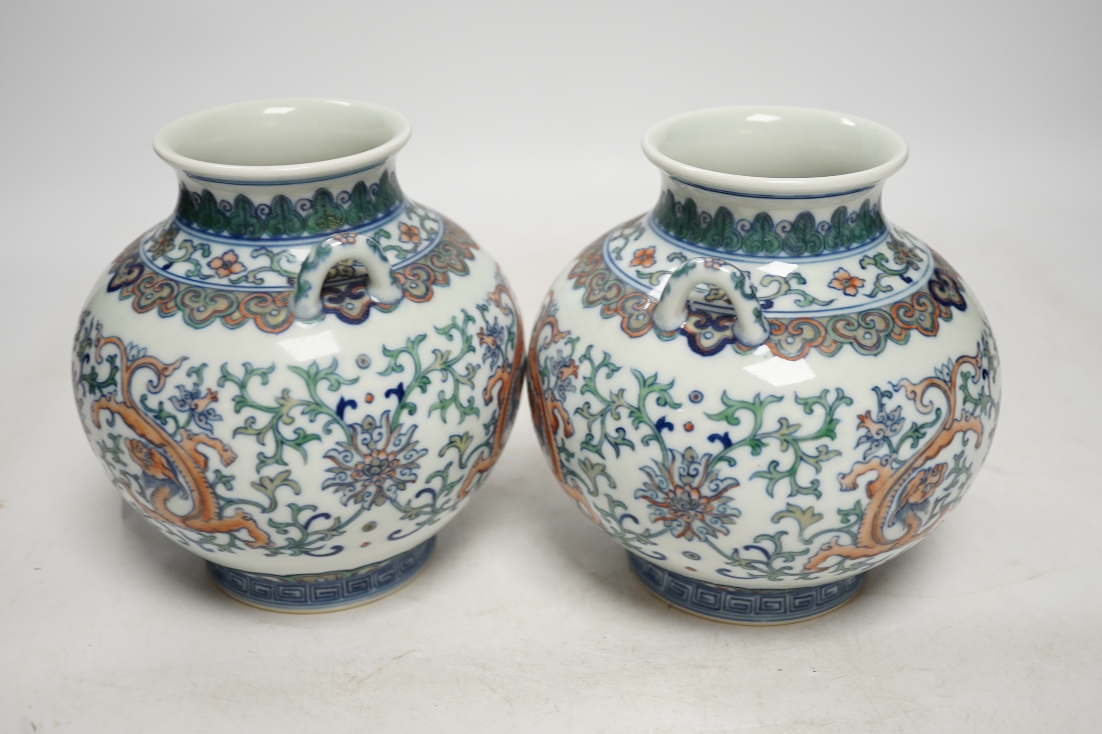 A pair of Chinese porcelain doucai twin handled ‘dragon’ jars, 14cm high. Condition - good